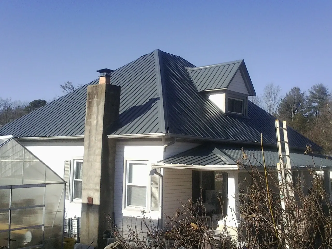 Dark blue standing seam metal roof on a white farmhouse with dormer — Slate & Tile Roof Repair by Roofing Brothers in Terrace Park