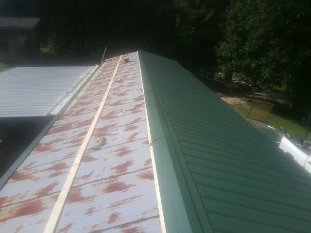 Old rusted panels beside newly installed green metal roofing — Wind Damage Roof Repair by Roofing Brothers in Terrace Park