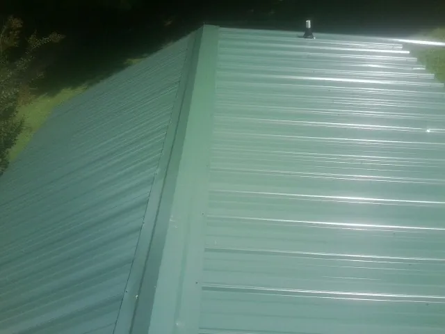 New green metal panels meeting at the ridge of a roof — Flat Roof Repair work by our crew in Terrace Park
