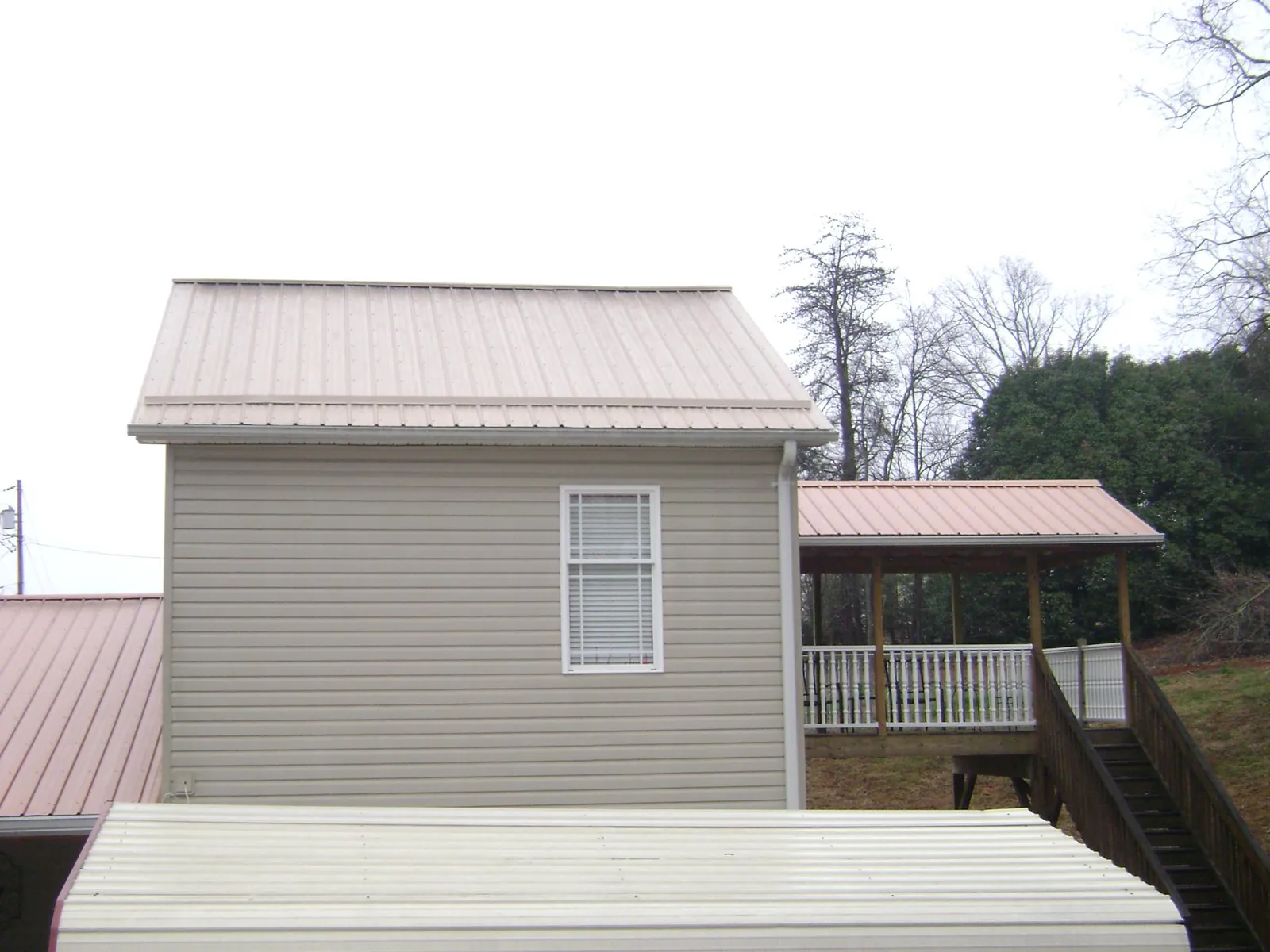 Tan metal roofs on a two story addition and attached porch, from a Roof Replacement job in Terrace Park
