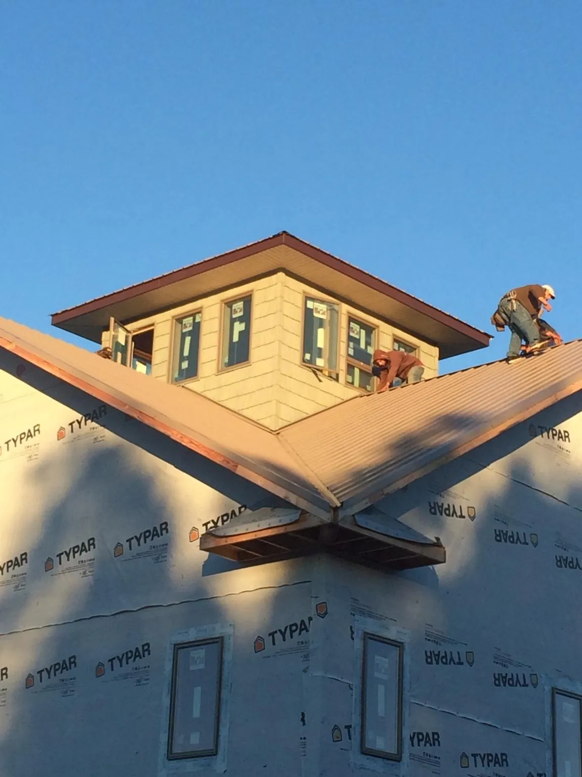 Roofers working around a rooftop cupola on a new metal roof at sunset — Roof Waterproofing in Terrace Park by Roofing Brothers